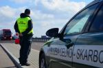samochód służby celno-skarbowej, obok funkcjonariusz na drodze ekspresowej zatrzymuje tira do kontroli